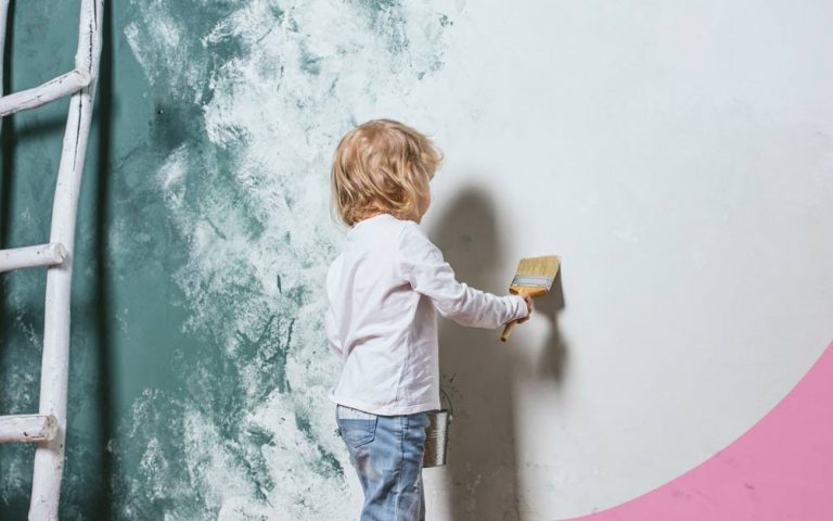 niño pintando pared de una habitación