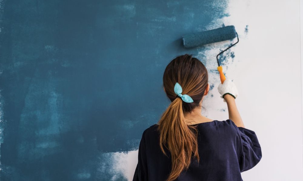 mujer pintando pared de color azul